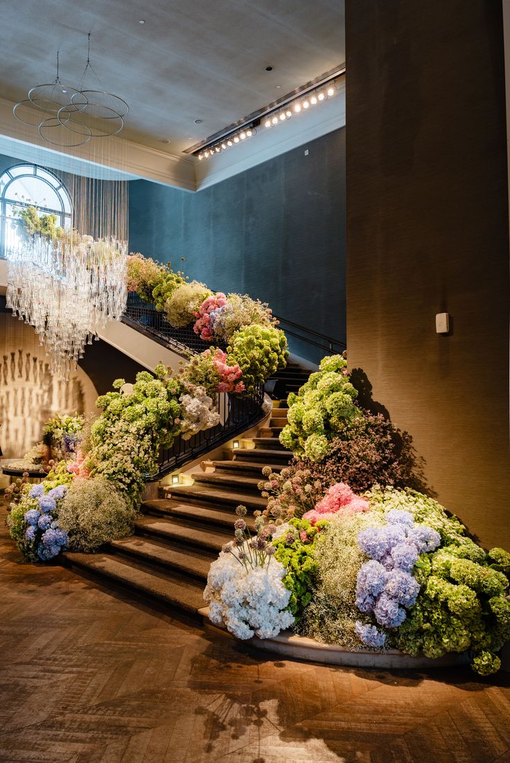 Grand escalier fleuri d’hortensias bleus et verts, de roses et de gypsophile, sous un lustre de cristal