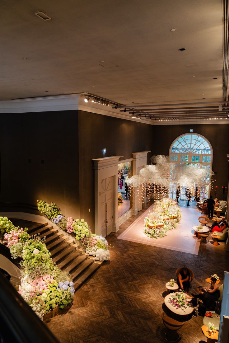Salle de réception avec escalier fleuri et nuage de fleurs blanches au fond