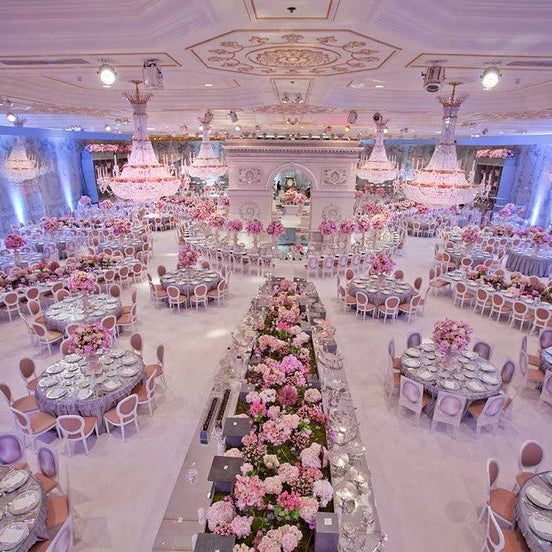 Salle de réception de mariage, tables rondes et allée centrale fleuries de roses roses et blanches
