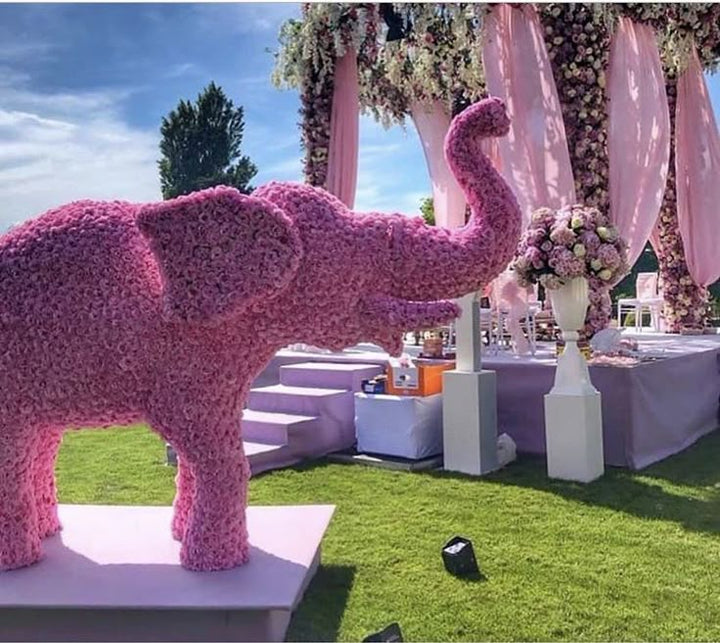 Éléphant recouvert de fleurs roses sur une pelouse