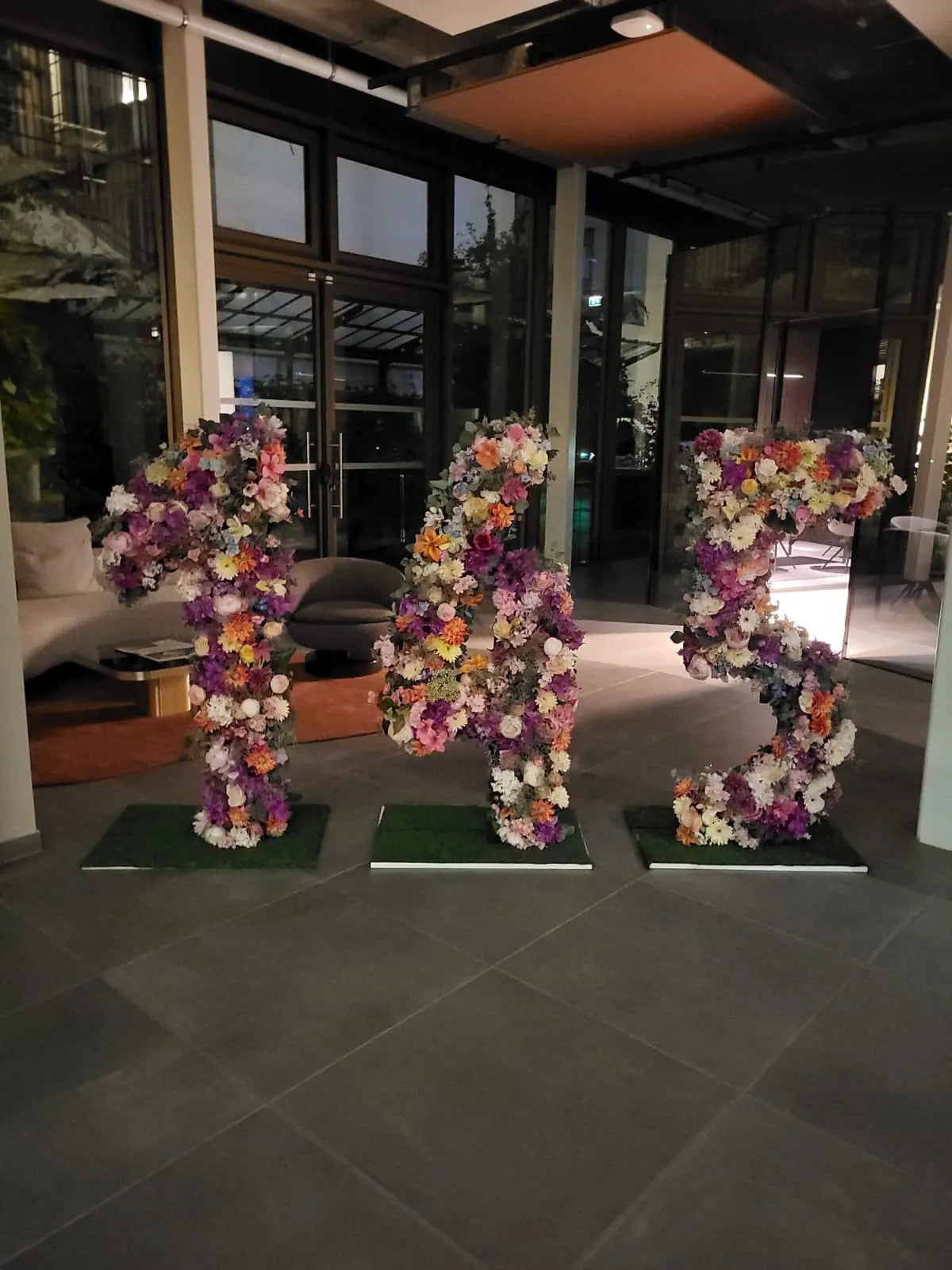 Trois chiffres géants couverts de fleurs, posés dans le hall le soir