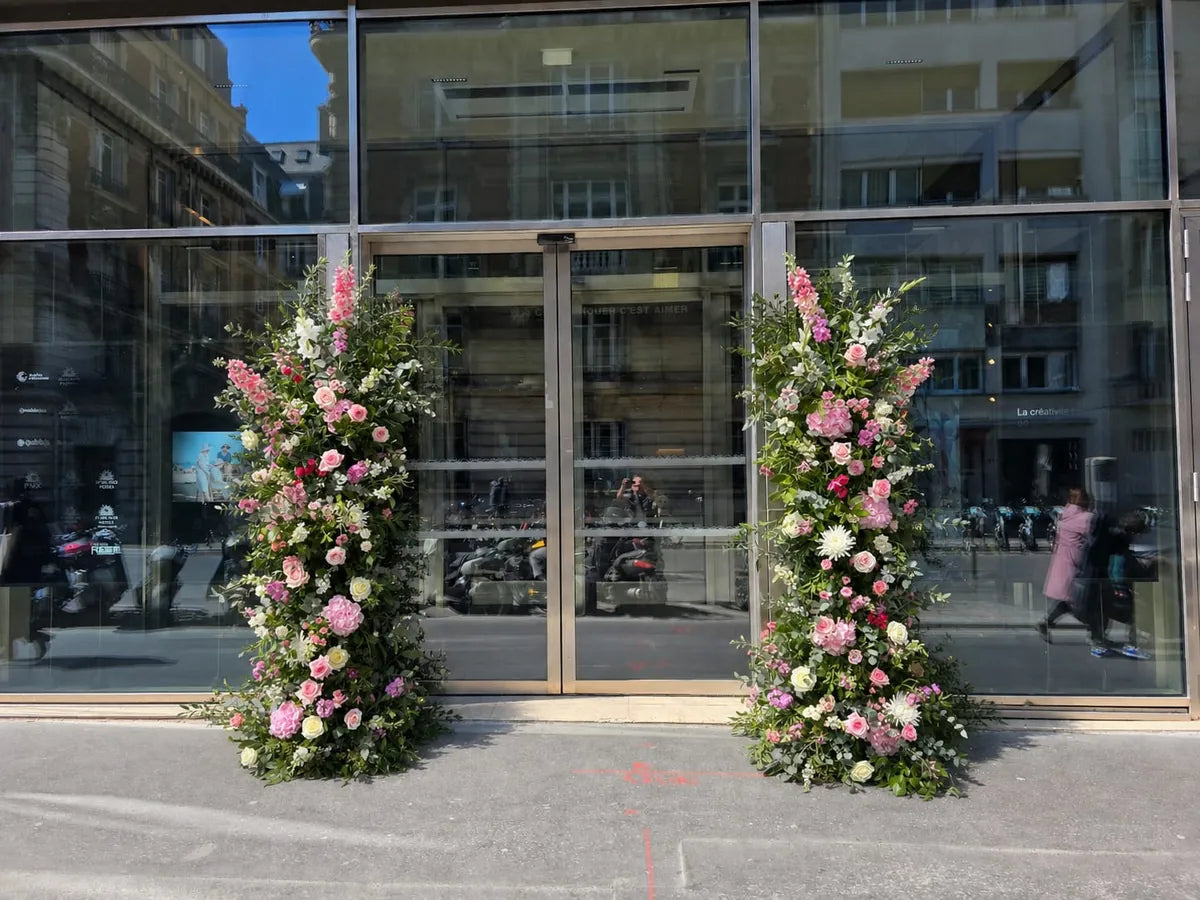 Deux colonnes de fleurs roses et blanches de chaque côté des portes vitrées d’un siège d’entreprise