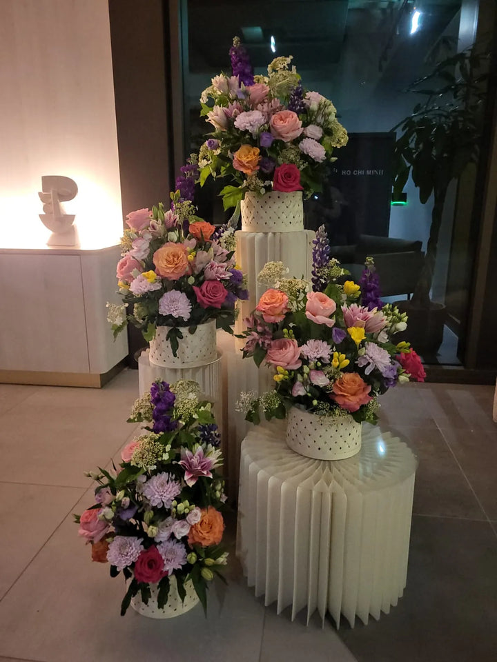 Compositions de roses et de lys en cascade sur des socles blancs plissés