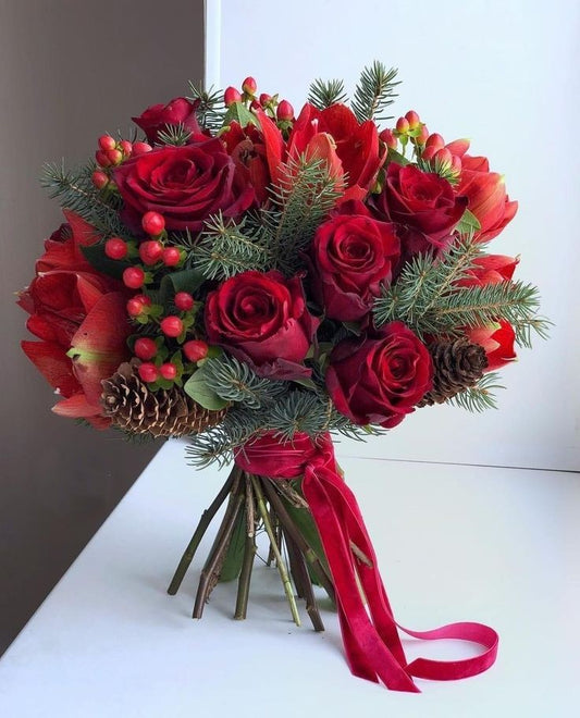 Roses rouges et corail : un dégradé de couleurs chaudes symbolisant la passion et la joie des fêtes
Baies rouges décoratives : apportant une touche de gaieté et de couleur
Branches de sapin : pour une ambiance authentiquement hivernale et parfumée
Pommes de pin naturelles : ajoutant une note rustique et chaleureuse
Feuillage vert : sublimant l'ensemble avec fraîcheur