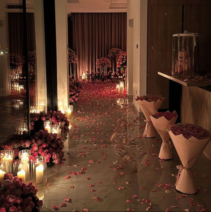 Allée de pétales de roses bordée de bougies et de vases de fleurs rouges