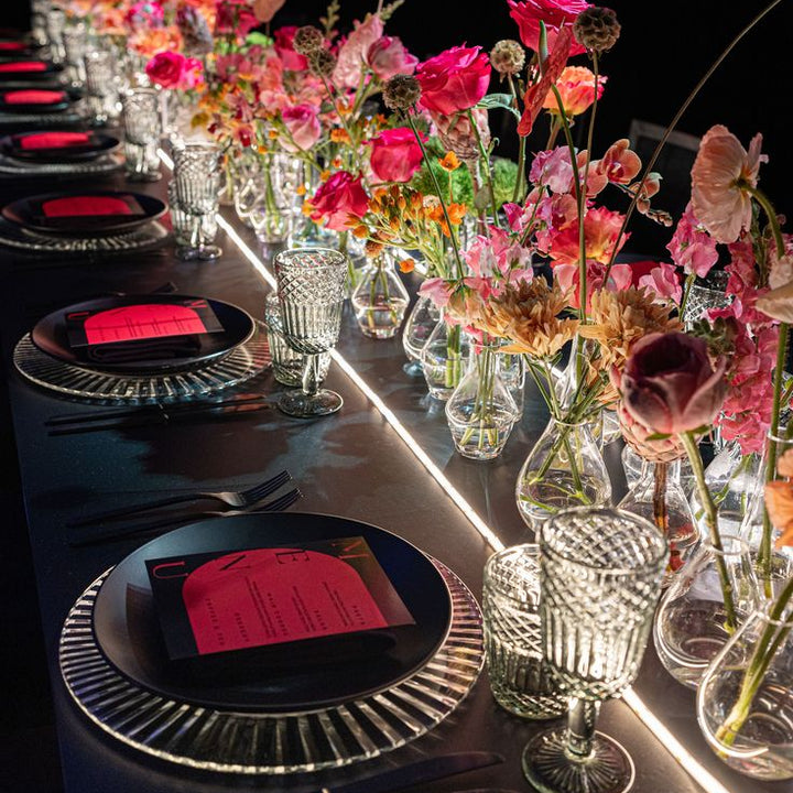 Table de cocktail dressée, vases de roses rouges et verres en cristal